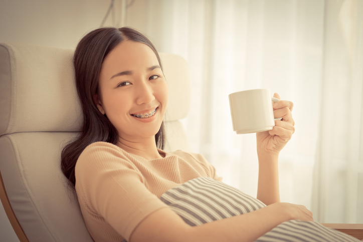Girl with braces smiling with a cup in her hand